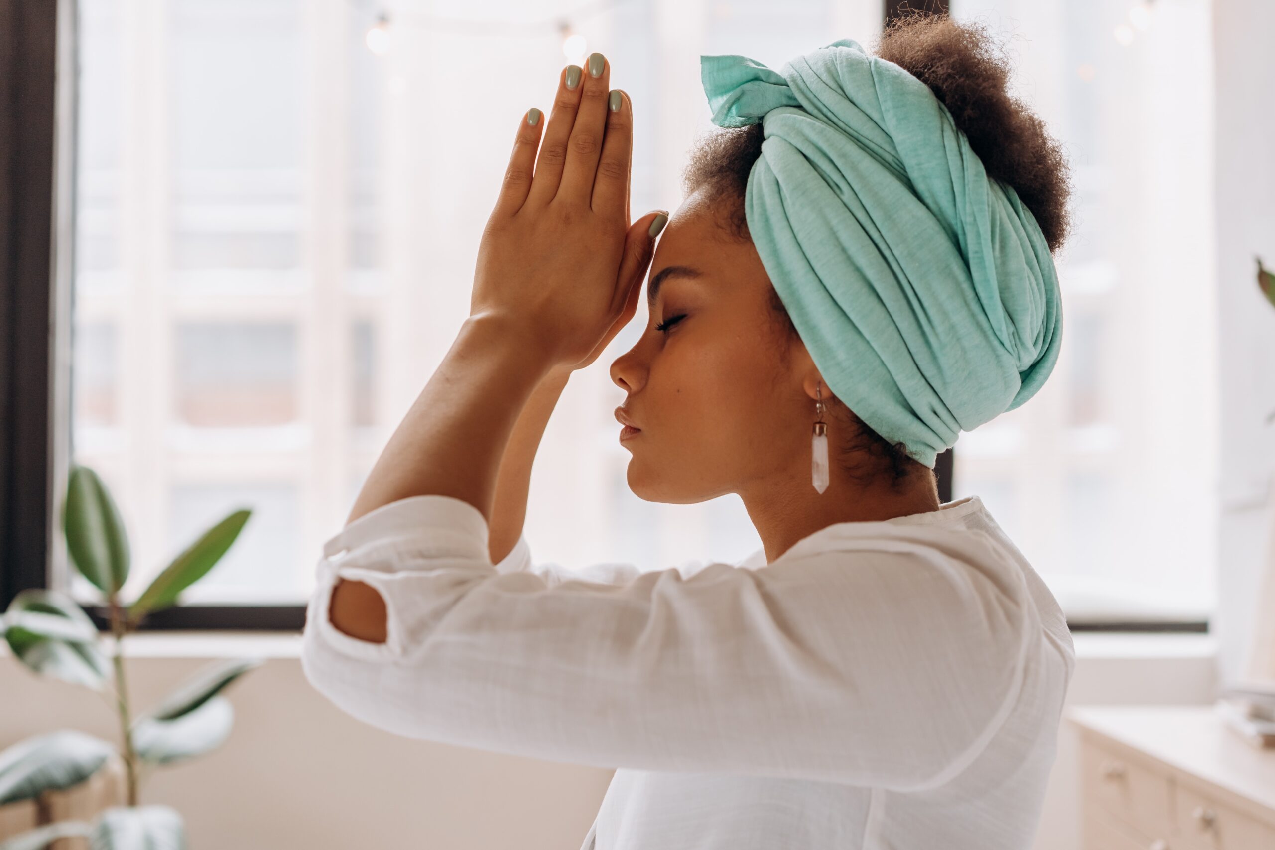 Woman with head wrap touching palms together at forehead